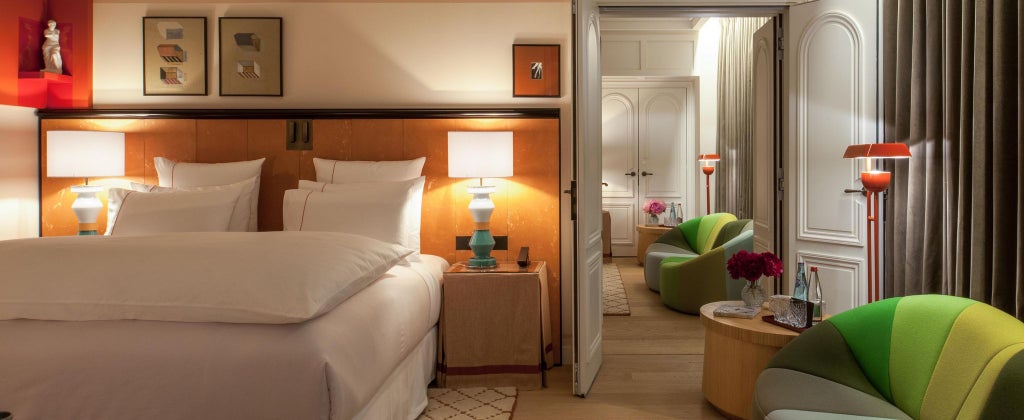 Elegant Deluxe hotel room with contemporary design, featuring soft neutral tones, luxurious bedding, and sophisticated minimalist French interior styling