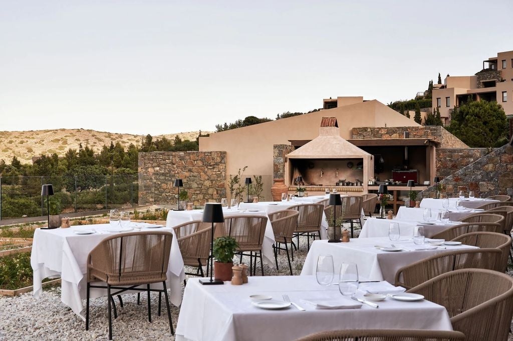 Multi-level infinity pools overlooking Aegean Sea, whitewashed Mediterranean architecture nestled into cliffside, luxury cabanas at sunset