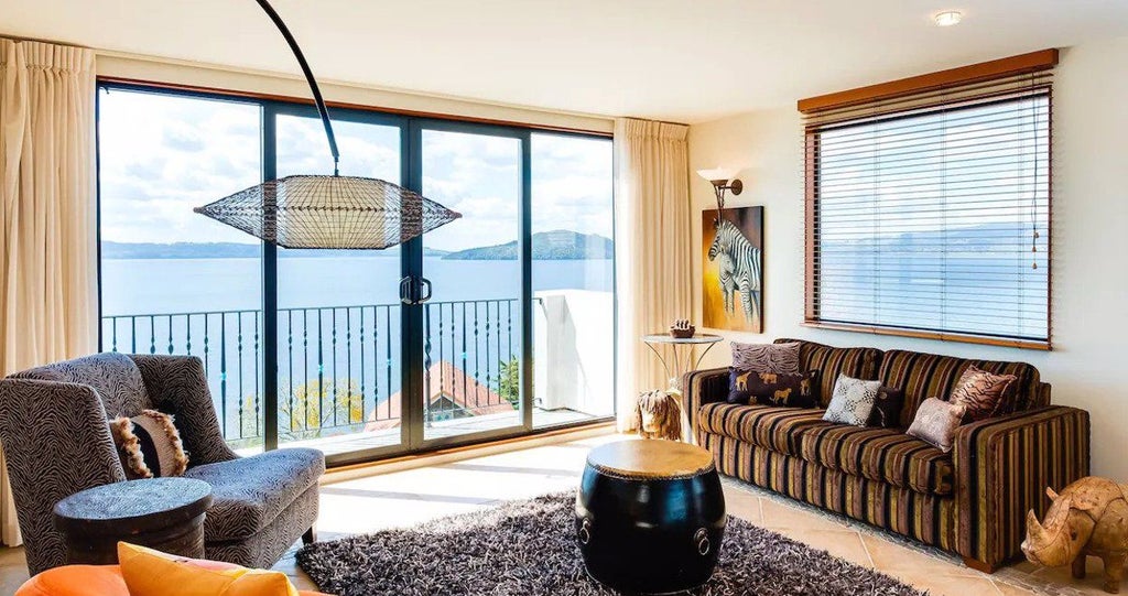 Spacious 4-bedroom luxury villa with panoramic lake and mountain views, featuring elegant contemporary design and expansive glass windows in New Zealand.