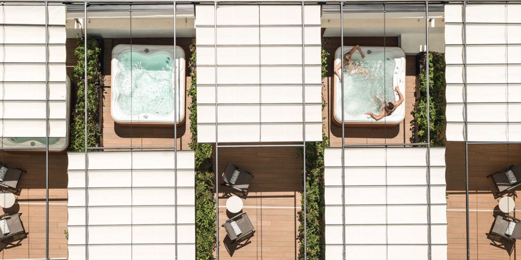 Luxurious rooftop terrace of a modern boutique hotel in Palma de Mallorca, featuring sleek pool, sun loungers, and panoramic cityscape