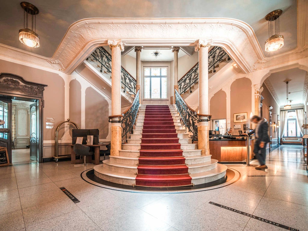 Elegant Swiss hotel with Belle Époque facade, featuring ornate white architecture, classic balconies and panoramic mountain views of Interlaken