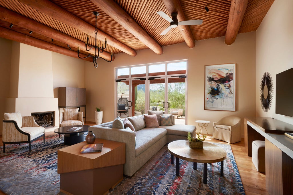 Luxury desert resort with adobe-style buildings nestled among red rocks, featuring a curved pool and manicured gardens at sunset