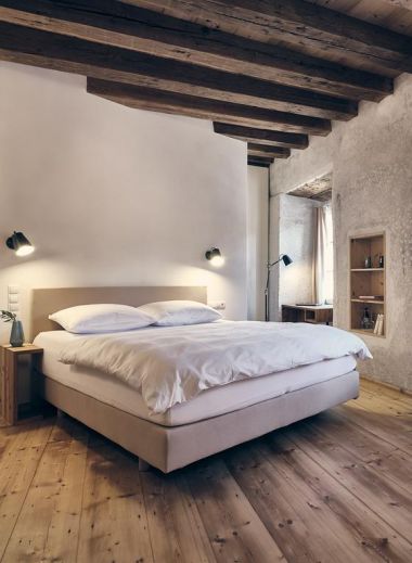 Modern alpine hotel exterior with white facade, timber accents, and large windows, nestled in a scenic mountainous Austrian setting