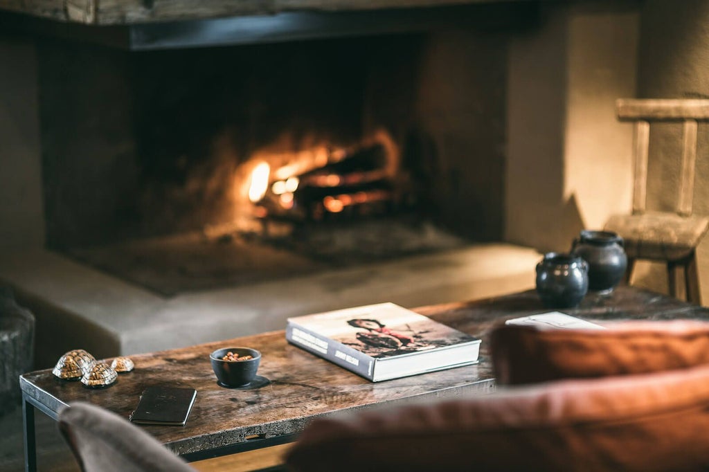 Luxurious alpine chalet with snow-covered peaks, warm wooden interiors, elegant fireplace, and cozy fur throws in a serene French mountain landscape