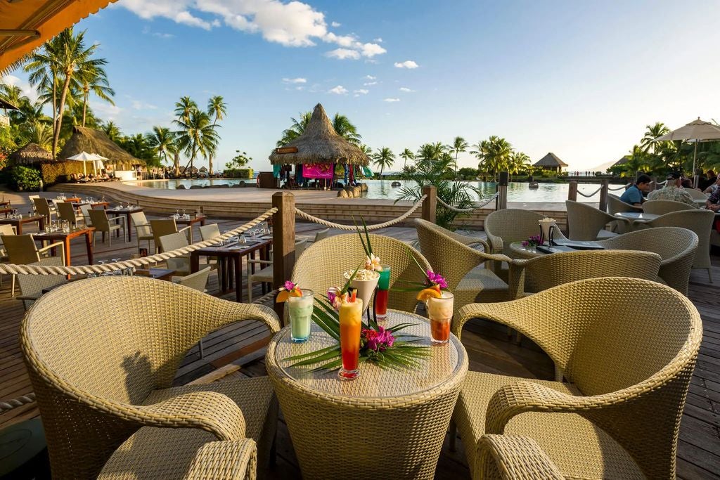 Luxurious overwater bungalows at Intercontinental Tahiti stretching into turquoise lagoon, backed by lush mountains and palm trees