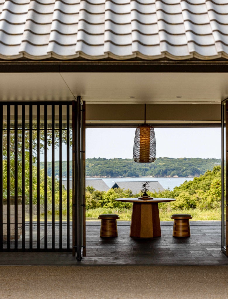 Modern Japanese luxury ryokan with private outdoor onsen bath overlooking Ago Bay, surrounded by lush forest and traditional gardens