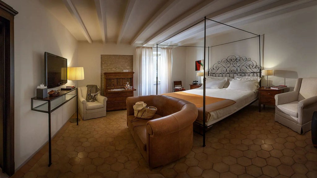 Elegant stone-walled suite at Palazzo Seneca with plush king bed, antique wooden furnishings, and soft warm lighting in a rustic Umbrian setting