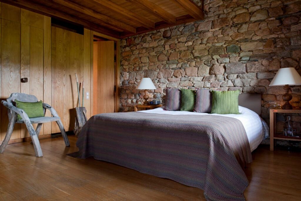 Rustic luxury dragon-themed cottage bedroom with wooden beams, plush bedding, and elegant French countryside decor at Domaine des Etangs resort