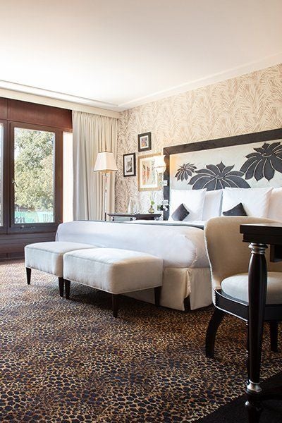 Elegant executive hotel room with lake view, plush white bedding, contemporary design, and soft neutral tones at Swiss luxury spa resort