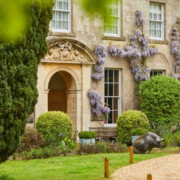 Luxurious countryside hotel nestled in South Downs, featuring rustic stone exterior, lush green landscape, and elegant farmhouse-style architecture with warm natural lighting