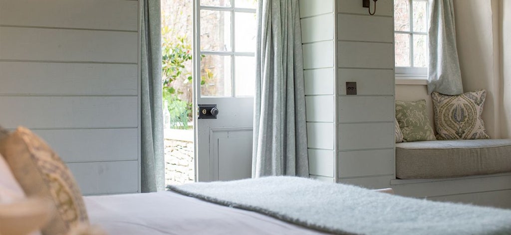 Elegant rustic bedroom in Coach House at Middleton Lodge, featuring soft neutral tones, plush bedding, exposed wooden beams, and refined countryside charm.