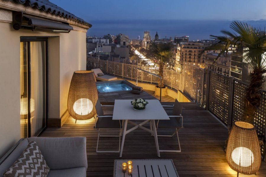 Elegant five-star Majestic Hotel & Spa facade with ornate stone architecture, wrought-iron balconies and towering palm trees in Barcelona