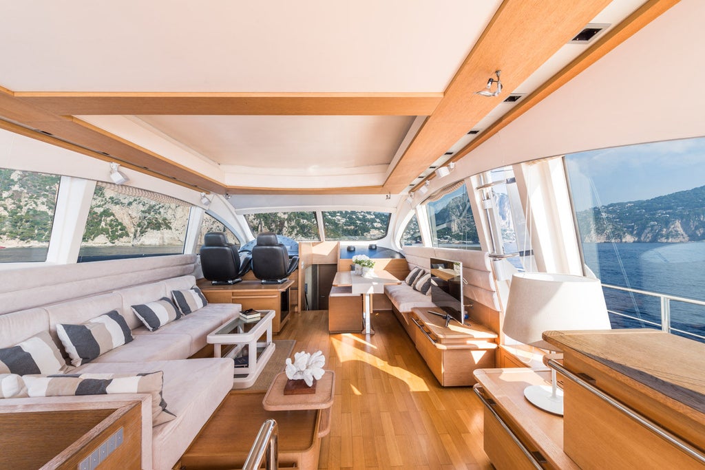 Elegant private yacht hotel on Italian coast with white exterior, panoramic windows, and luxurious wooden deck overlooking Mediterranean waters