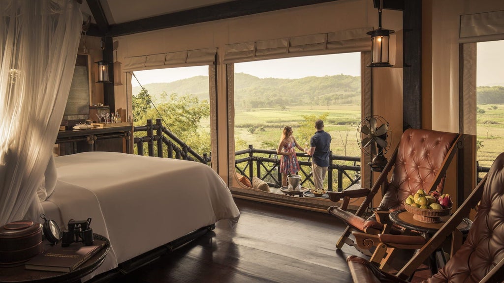 Luxury safari-style tent villa with teak deck overlooking misty jungle canopy at sunset, nestled in Thailand's Golden Triangle