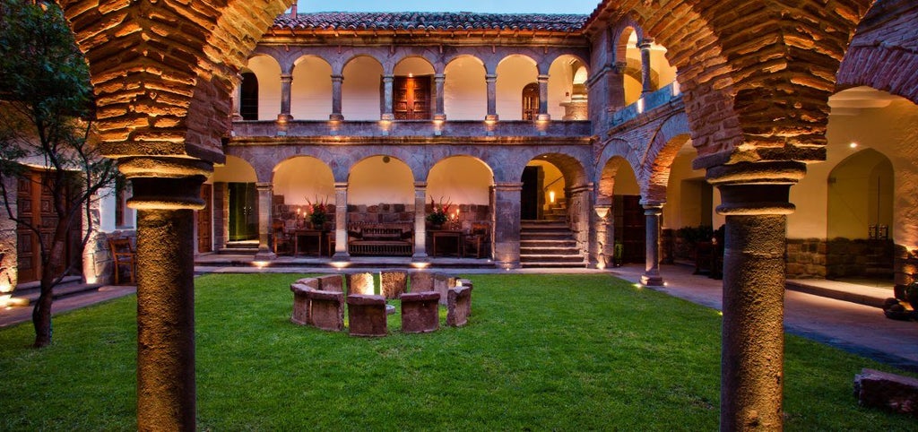 Historic luxury hotel with stone archways and courtyard, featuring Colonial-era architecture and elegant potted plants in Cusco, Peru