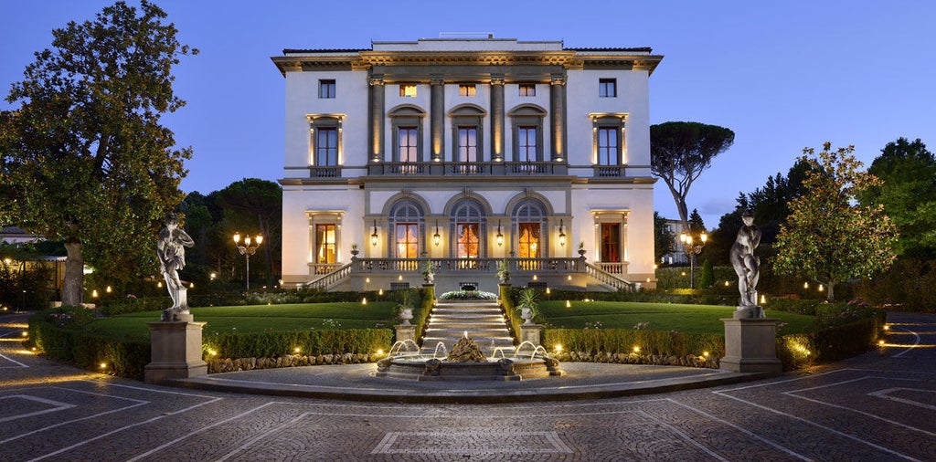 Elegant Renaissance-style Italian hotel Villa Cora with ornate facade, surrounded by manicured gardens and cypress trees in golden sunlight