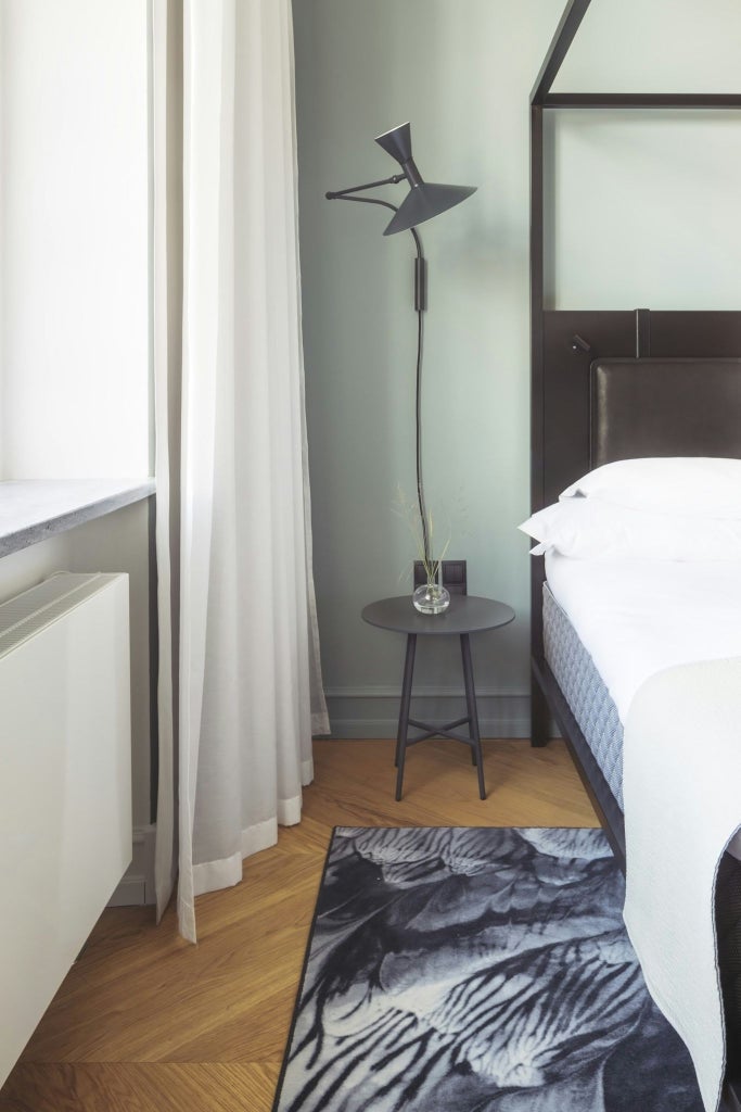 Minimalist Scandinavian hotel room with elegant neutral tones, plush white bedding, contemporary furniture, and soft natural lighting at luxury Copenhagen hotel