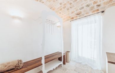 Luxurious stone-walled Deluxe Lamia room at Borgo Canonica, featuring rustic white-draped bed and elegant traditional Italian countryside decor