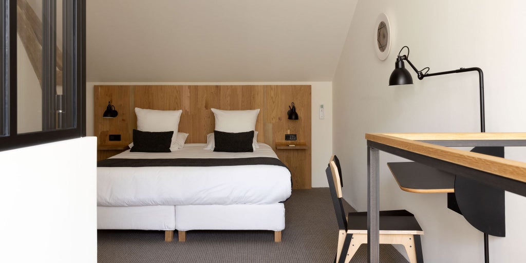 Minimalist white bedroom with elegant design in French château, featuring luxurious bed, clean lines, and soft natural light from expansive windows overlooking countryside