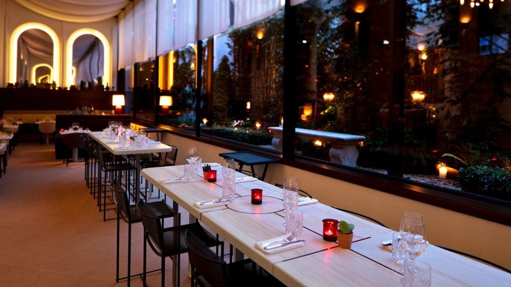 Opulent Parisian hotel exterior at dusk, featuring elegant stone facade, soft amber lighting, and chic French architectural details