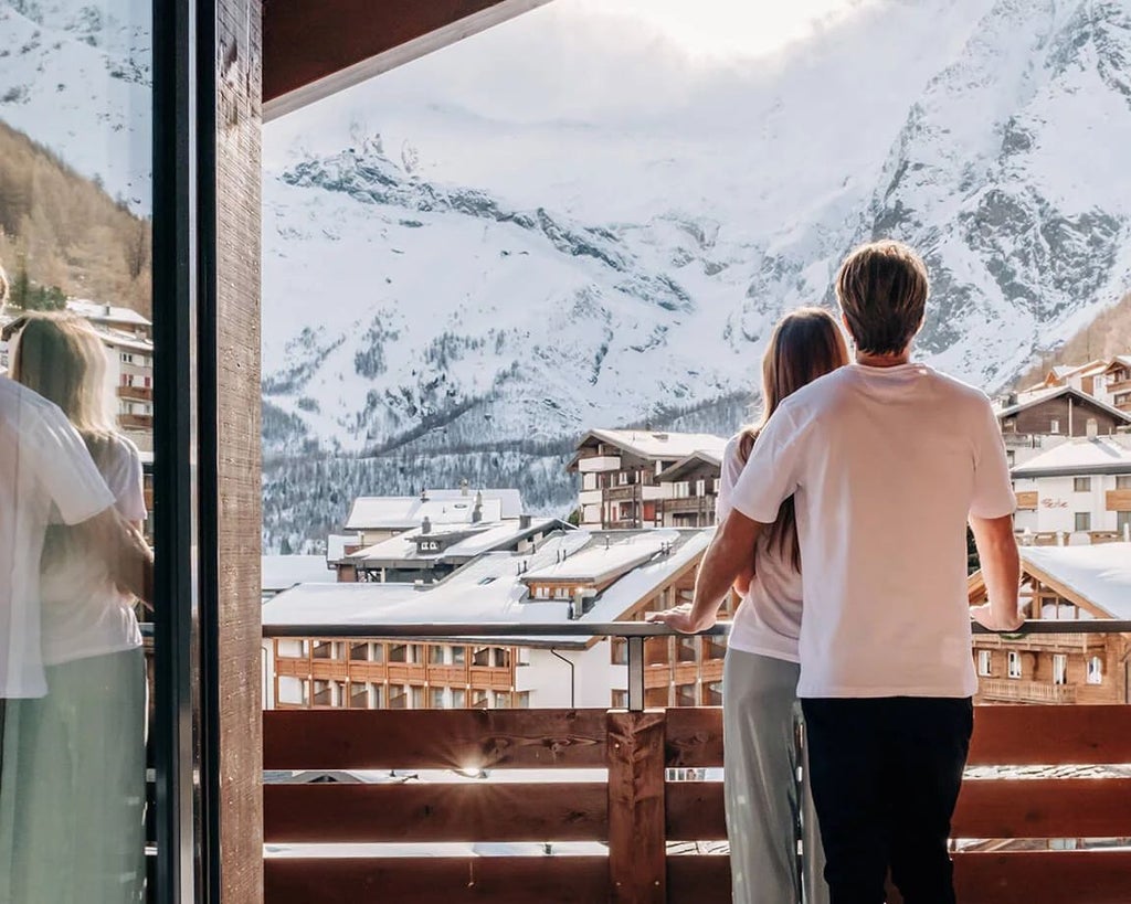 Luxurious alpine hotel nestled in scenic Swiss mountains, featuring rustic wooden exterior, snow-capped peaks, and elegant chalet-style architecture at sunset.