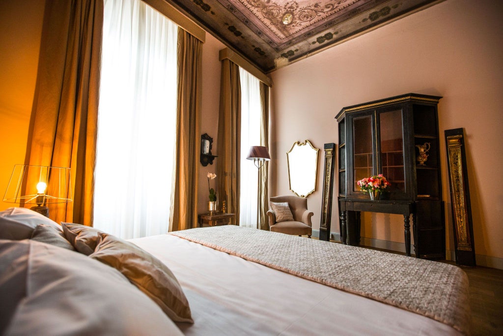 Elegant Italian-style deluxe hotel room with ornate antique furnishings, plush white bedding, and vintage architectural details in warm neutral tones