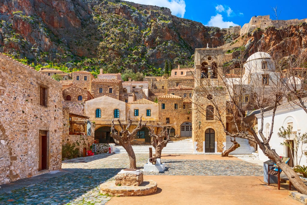 Elegant stone walkway winding through historic Monemvasia, Byzantine castle walls, azure Aegean Sea backdrop, golden sunlight illuminating medieval architecture