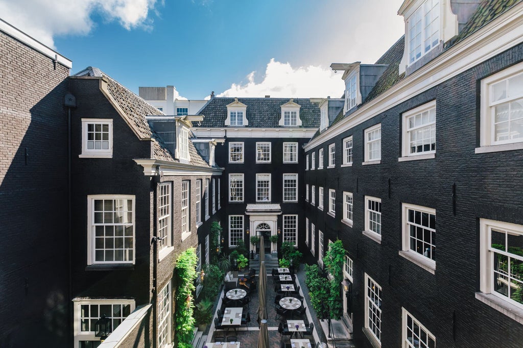 Elegant 17th-century boutique hotel in Amsterdam with classic red brick facade, arched windows and ornate iron balconies along canal front