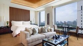 Elegant executive suite with panoramic Tokyo skyline view, contemporary minimalist design, floor-to-ceiling windows, neutral color palette, and sleek modern furnishings