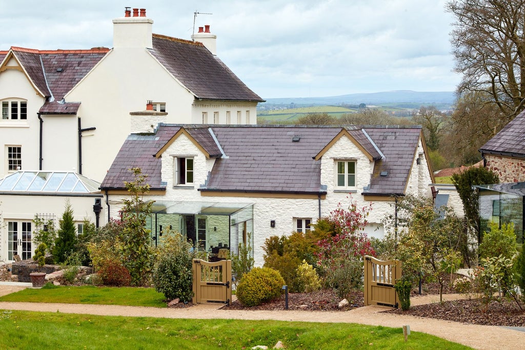 Luxurious wooden-paneled hotel room with soft neutral tones, plush bedding, and elegant rustic details at Grove of Narberth's Byre suite in rural United Kingdom.