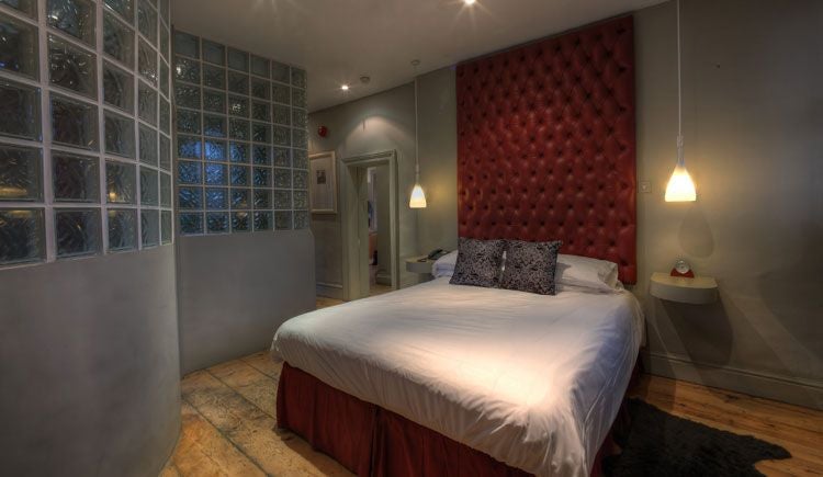 Elegant boutique hotel suite with plush king bed, soft neutral decor, rich wooden furniture, and refined textural accents in a sophisticated UK accommodation space