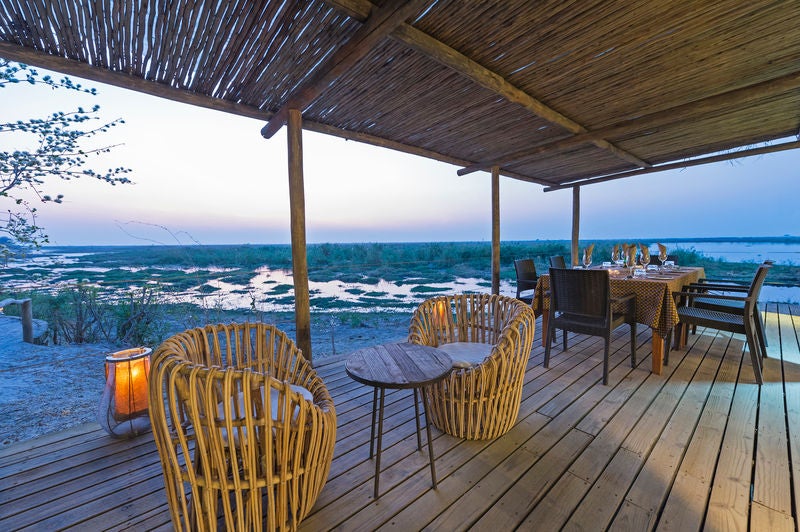 Elevated luxury safari tent overlooking Linyanti wetlands, featuring canvas walls, wooden deck, and panoramic wilderness views