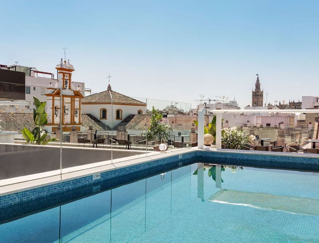 Five-star Radisson Collection hotel exterior in Seville with elegant modern facade, glass walls and luxury entrance canopy at night