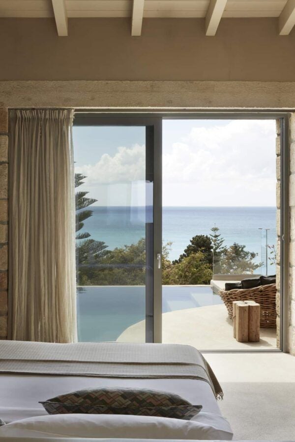 Minimalist luxury raw stone hotel room with private pool, earthy neutral tones, elegant minimalist design overlooking scenic Greek landscape