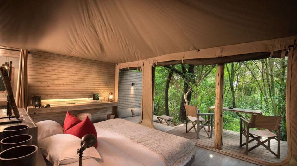 Canvas tented suite with private deck overlooking Masai Mara savanna, featuring elegant safari furnishings and panoramic wilderness views