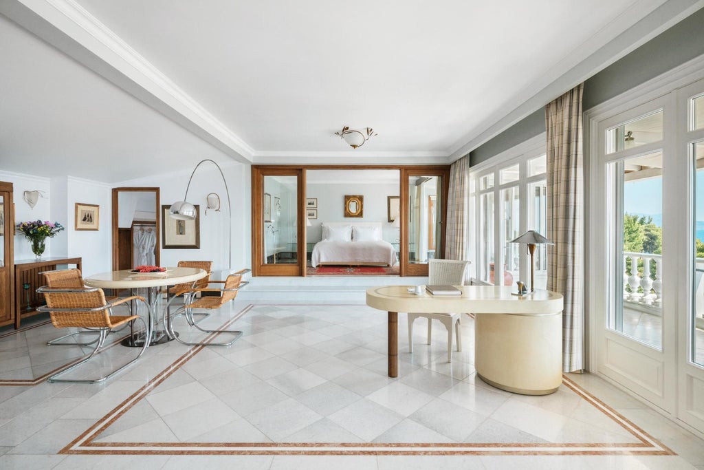 Luxurious Mediterranean Suite with panoramic sea view, elegant white furnishings, king-sized bed, and private balcony overlooking azure Aegean waters at seaside resort