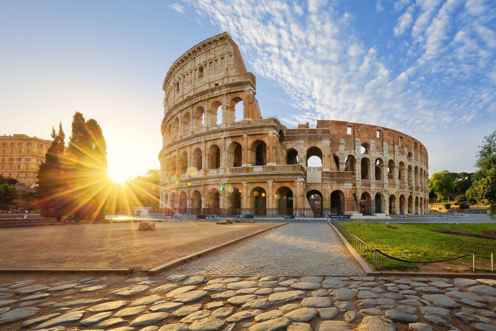 Elegant ancient Roman ruins including majestic Colosseum lit by golden sunset, with grand stone arches and columns towering skyward