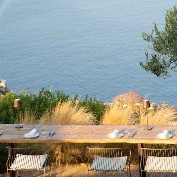 Luxurious whitewashed Cycladic hotel overlooking azure Aegean Sea, with minimalist infinity pool and elegant stone terrace at sunset in Sifnos, Greece