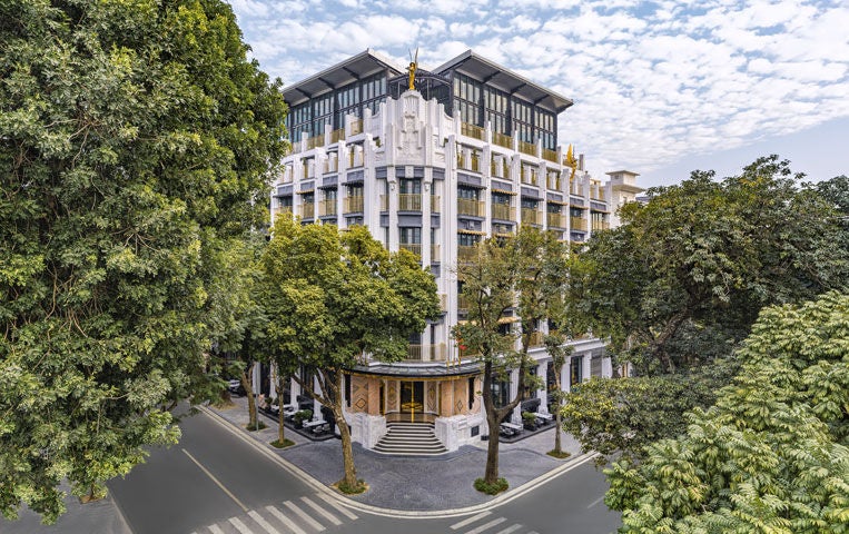 Opulent art deco hotel facade in Hanoi featuring ornate columns, grand balconies, and intricate gold accents against white exterior walls