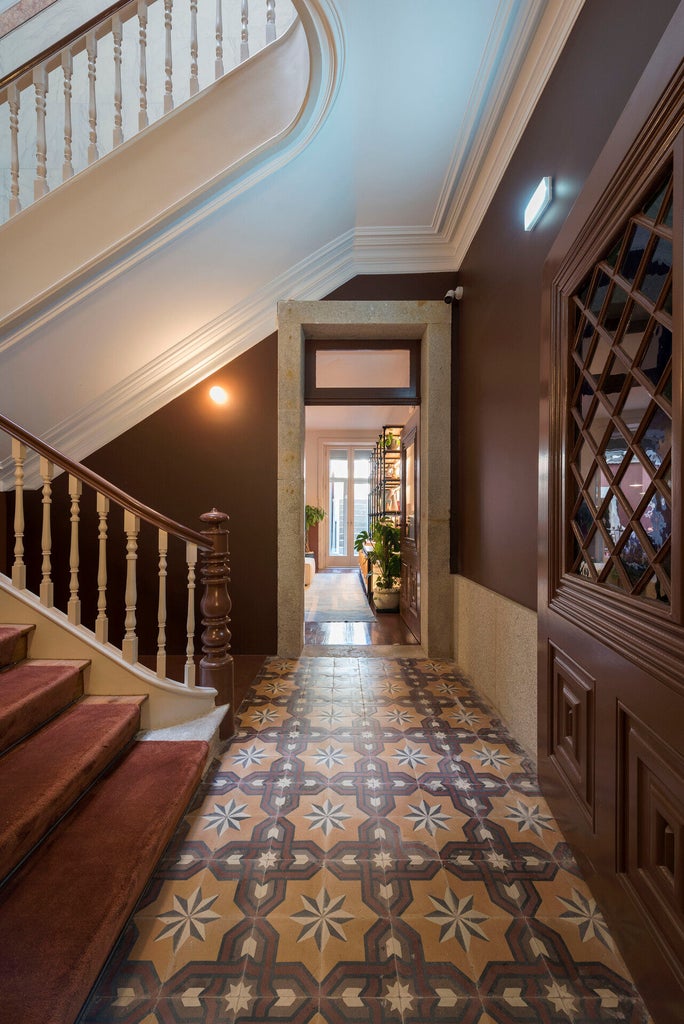 Elegant boutique guesthouse with stone facade, featuring ornate iron balconies and tall windows draped with white curtains in Porto