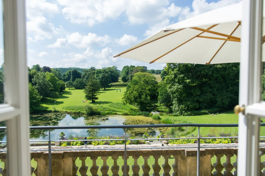 Luxurious stone manor hotel nestled in lush Cotswolds countryside, featuring elegant architecture with modern design elements and manicured gardens