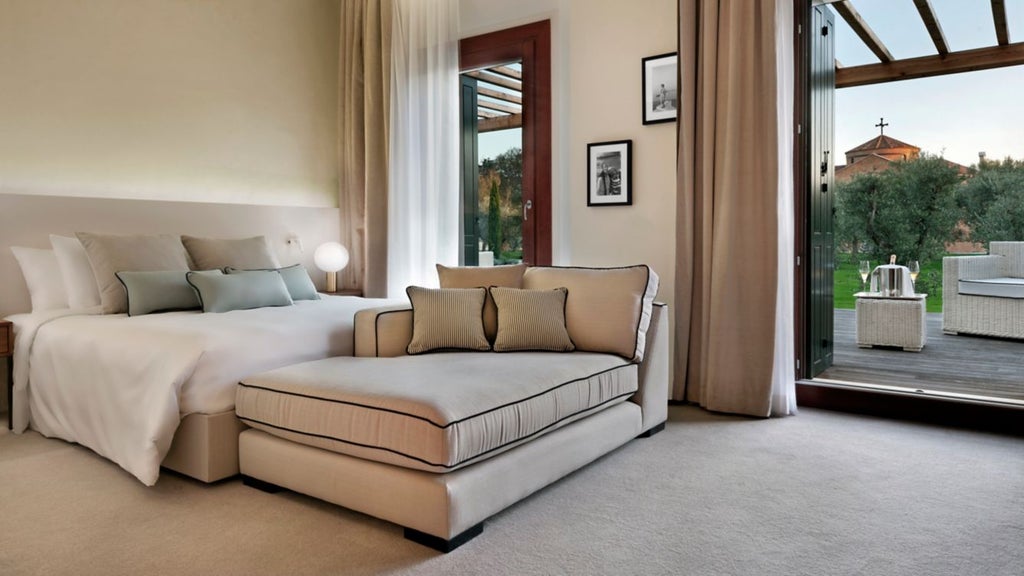 Elegant hotel room with floor-to-ceiling windows, king bed with white linens, modern decor, and private terrace overlooking Venice gardens