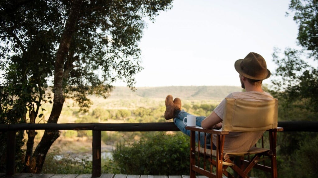 Luxurious canvas tent with wooden deck overlooking Mara River, surrounded by African savanna at dusk, lanterns casting warm glow