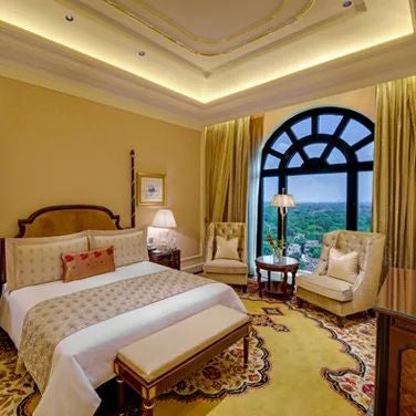 Elegant royal club room at a luxury hotel, featuring rich golden accents, plush king bed, and intricate Indian-inspired decor with city skyline view