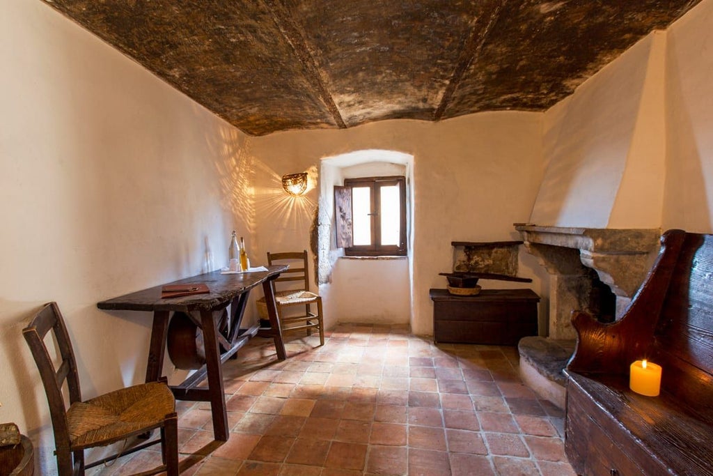 Rustic stone-walled bedroom with antique wooden furnishings, soft linen bedding, and warm candlelight in a historic Italian hotel room