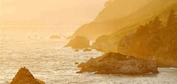 Luxurious Big Sur Suite at Ventana overlooking dramatic coastal landscape with elegant wood furnishings, expansive windows, and natural Pacific coastline vista