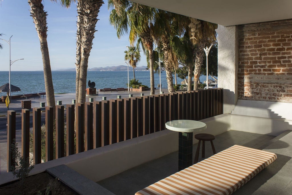 Sunset illuminates beachfront luxury villa with infinity pool, white architecture, and palm trees at scenic Mexican coastal resort