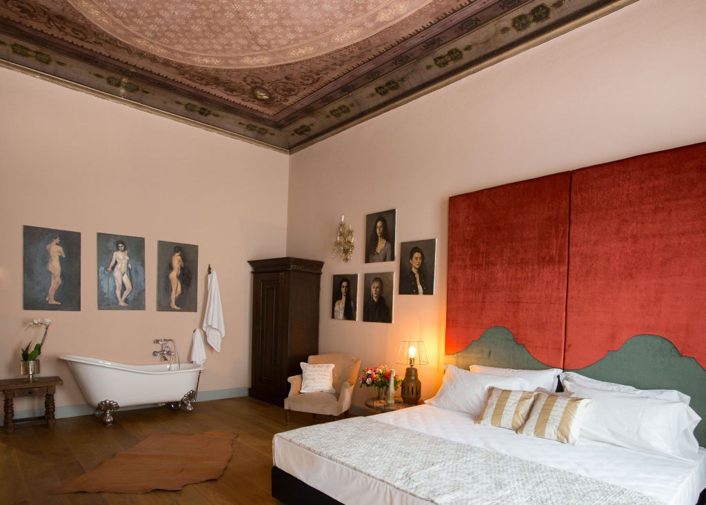 Elegant Italian boutique hotel room with antique furnishings, ornate chandeliers, and plush bedding in warm neutral tones at SoprArno Suites, Florence