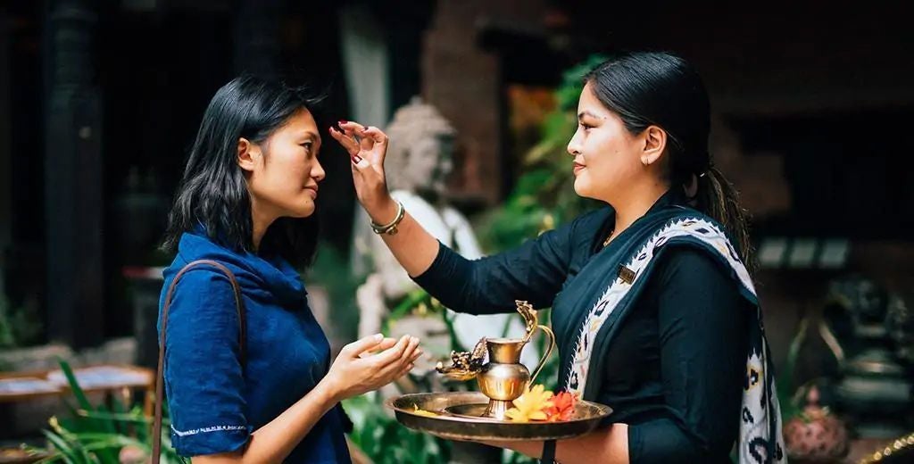 Traditional Nepalese palace-style hotel with ornate wooden carvings, red brick walls, and courtyard featuring decorative columns and artisan details