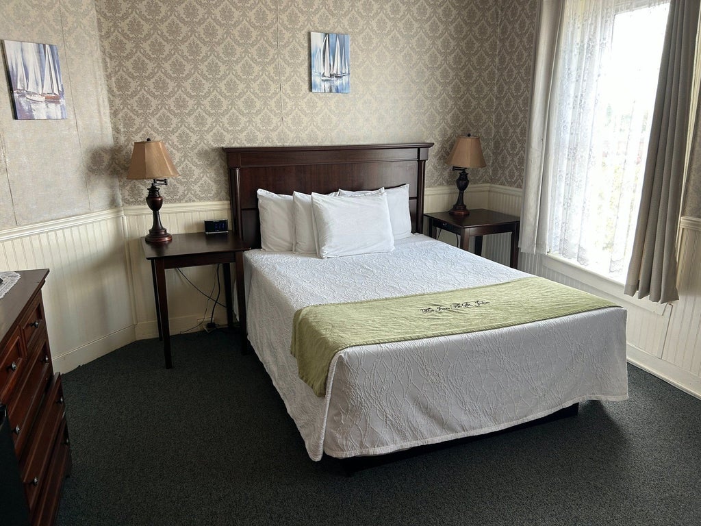 Elegant traditional hotel room with plush queen bed, classic wood furnishings, soft neutral color palette, and refined decorative accents in a serene setting